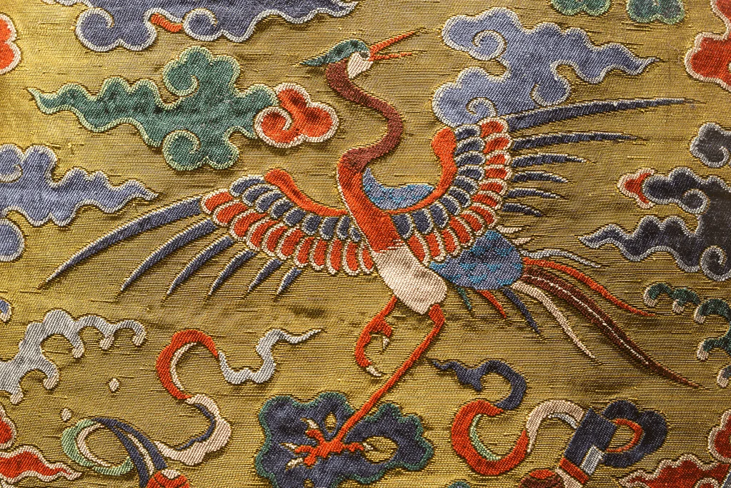 Image of a stunning and colorful Qing Dynasty embroidery showcasing a stork gracefully soaring amidst vibrant clouds, exemplifying the intricate craftsmanship of the era's textile artistry.